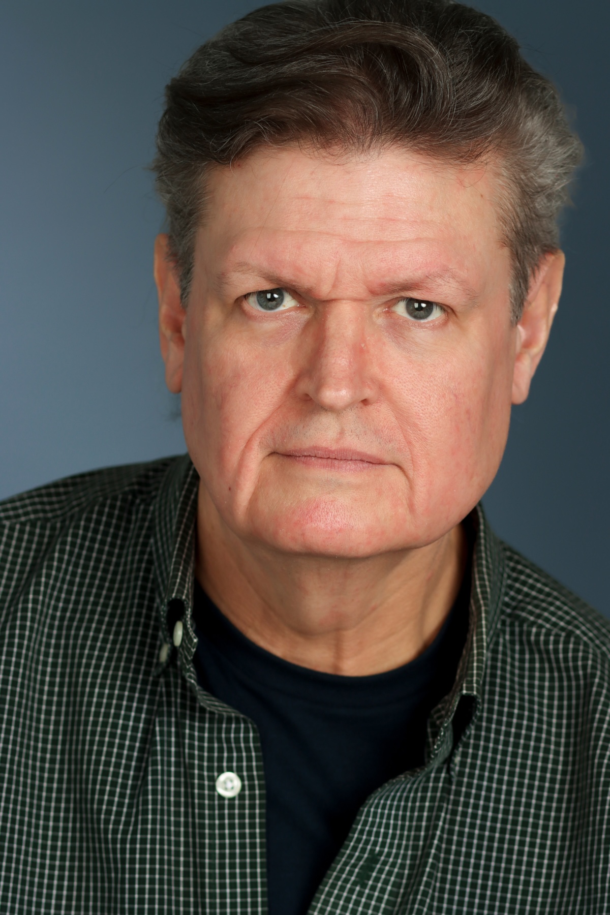 Headshot photo of Ed Jewett in a blue checkered shirt.